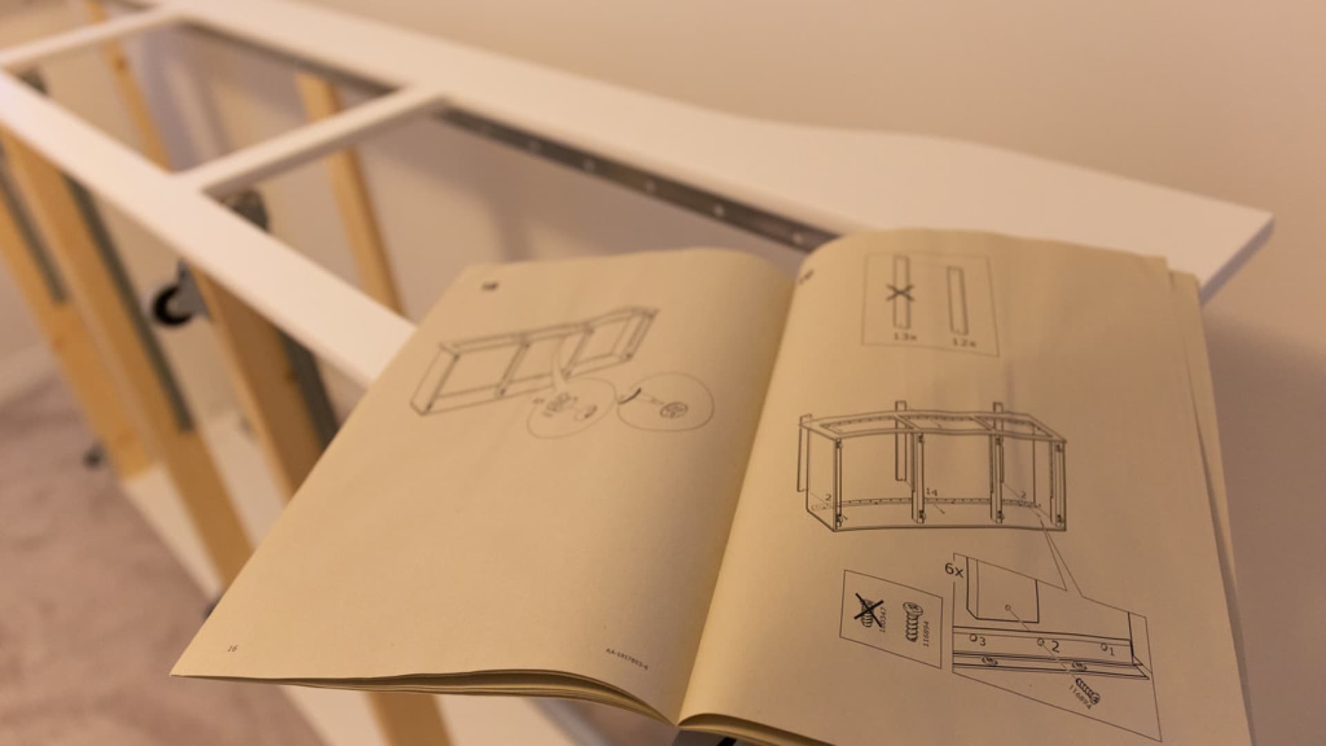Flat-pack furniture assembly instructions open on a partially built frame